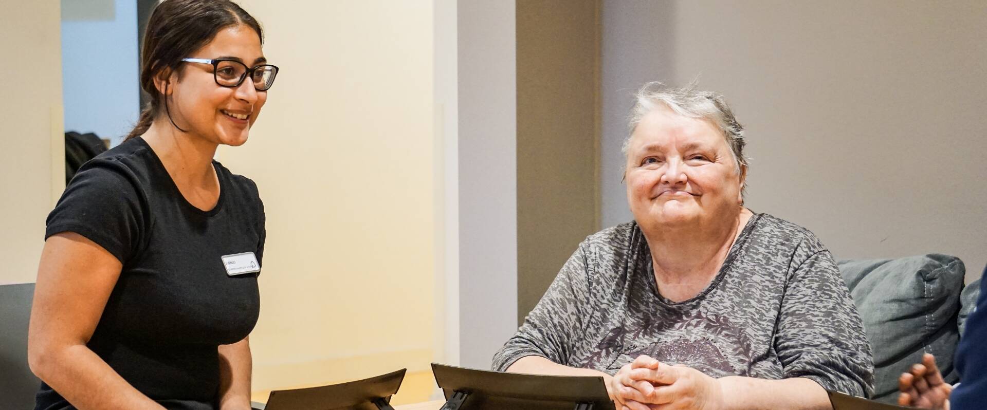 Pflegerin steht hinter einer älteren Dame